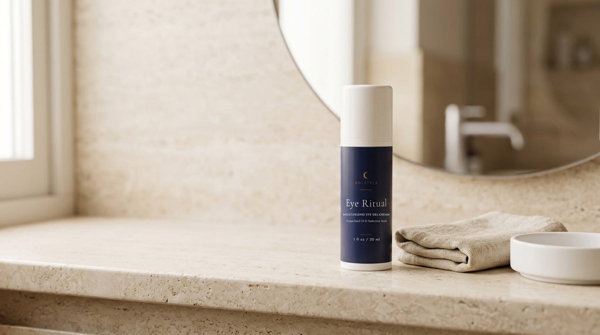 The navy Eye Ritual gel-cream bottle on a sunlit bathroom vanity beside a folded linen cloth